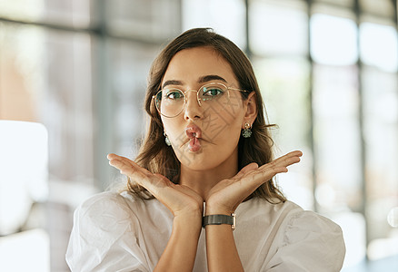 有趣的女商务人士戴着眼镜 双手放在脸下摆姿势 在办公室里用噘嘴做鱼脸鬼脸 顽皮的西班牙裔女企业家愚弄和愚蠢图片