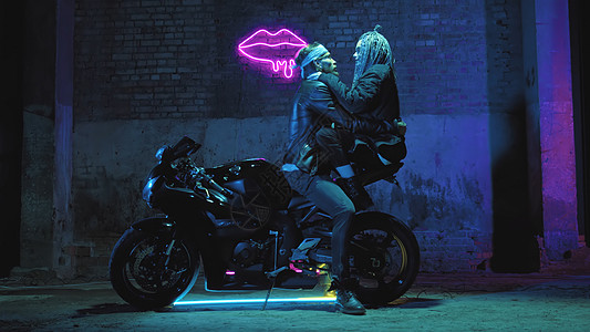 一个恋爱中的女孩和一个男人坐在一辆超级运动摩托车上 在霓虹灯的背景下调情拥抱自由恋人辫子魔法女士发动机运输男性行动力量图片