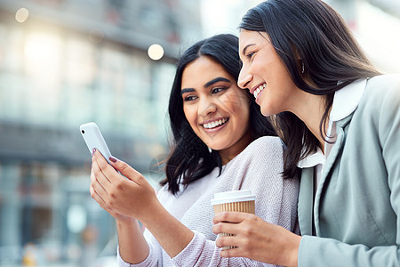 你认识的人越多 你的人脉就越大 两名年轻女商务人士在城市背景下使用智能手机的镜头背景图片