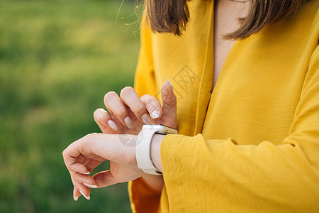 年轻女性在连接到互联网的现代智能手表上浏览通知 女性在小工具上使用触摸屏 室外女人手上的智能手表 使用智能手表的女孩图片