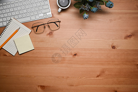 上面的键盘 眼镜 咖啡杯和木制桌上的笔记本图片