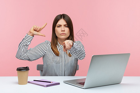 有情感的年轻女性 坐在办公室工作 有粉红色背景黑发指责欺凌失败讽刺电脑笔记本责备领导者打败图片