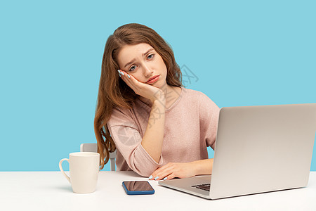 情感年轻女性在蓝背景的笔记本电脑上工作商务沮丧活力自由职业者孤独人士沉思商业休息办公室图片
