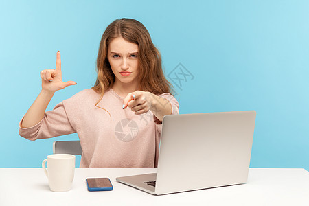 情感年轻女性在蓝背景的笔记本电脑上工作办公室损失手势失败者商业打败危机老板讽刺商务图片
