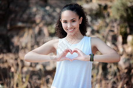 一个运动的年轻女子 站在外边用手形成心形 她能做点什么就能让你的心脏健康起来图片