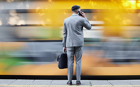 新的机会不断与他擦肩而过 一名年轻商务人士在上下班途中在火车站等火车时用手机通话的后视镜头图片
