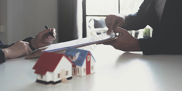 房地产经纪人与房屋模型手签合同 有合同保护它 在办公室签署适度的协议表 概念房地产 搬家或租房写作文档抵押管理人员商务交易起诉律图片