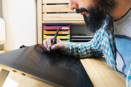 男子用铅笔在图形平板电脑上绘画图片