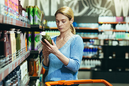 女性在超市货架上选择和检查产品图片