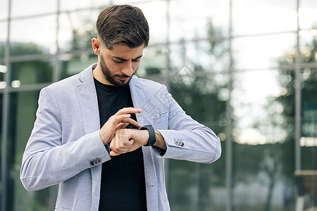 商务人士在通知上滚动显示 大胡子男子使用智能手表可穿戴腕带设备 男性检查脉冲智能手表应用程序 触摸屏可穿戴技术智能手环图片