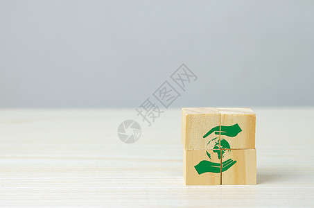 木制立方体 手和地球图标为净零 生态友好型商业和发展概念背景图片