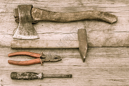 在旧木板表面的旧染色斧 锤子 钳子和螺丝刀高清图片