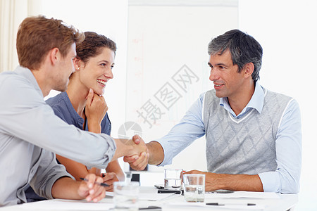 此次合并将使两家公司受益 两个商务人士在与一位女同事开会时握手图片