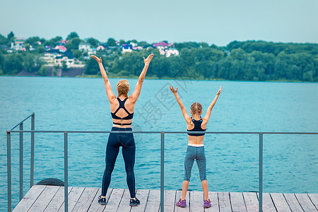 妇女和儿童正在手举手锻练娱乐培训师女士运动运动服地平线码头女孩身体沉思图片