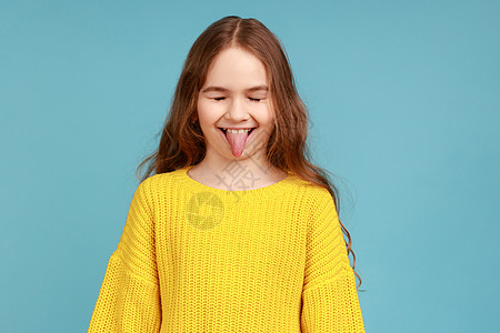 可笑的玩耍可爱小女孩的肖像 她用幼稚的表情露出舌头图片