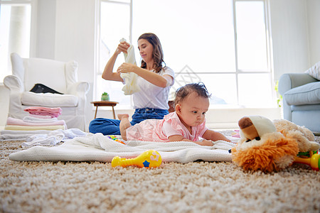我最喜欢的女孩 母亲折叠着衣服 而孩子在休息室玩耍的妈妈图片