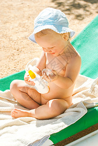 海滩上的孩子使用防晒霜预防奶油洗剂晒斑女儿晒黑身体母亲童年日光浴图片