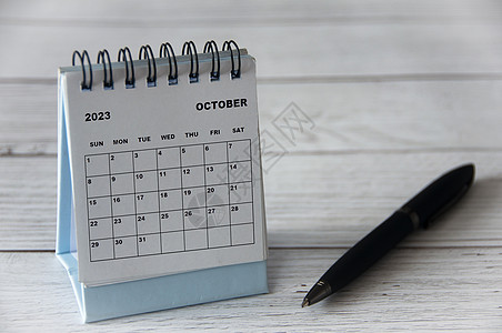 2023年10月白桌日历 木制桌子上有黑笔日程时间自由周年假期纪念日季节新年办公室空白图片