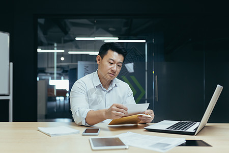 年轻商务人士 自由职业者 亚洲人处理文件 用笔写字 在笔记本电脑上工作顾问签名合同桌子技术企业家办公室男人职场职业图片