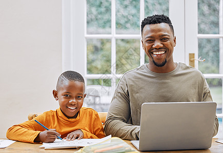 我们都有工作要做 一个年轻的父亲使用笔记本电脑 而他的儿子在家做功课图片