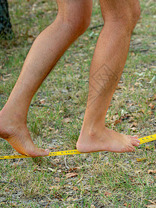 在一个公园的松绳上行走和平衡 在公园中钢丝运动衬垫行动闲暇自由日落肌肉福利享受图片
