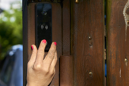 女人的手按着门铃 按在花园的木栅栏上生活访问手臂铃声客户住宅技术邻里深宅媒体图片