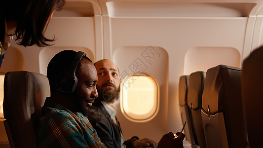 男乘客在飞机上与空服员交谈图片