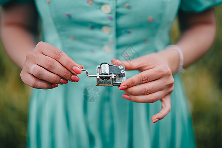 女性手旋转旧音乐盒机构的齿轮 复古小金属钟琴的女士转动杆 穿着复古连衣裙的女人正在听音乐图片