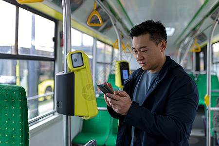 乘坐公共交通工具的快乐和成功的亚裔男性乘客用手机购买了一张机票 并取得了成功图片