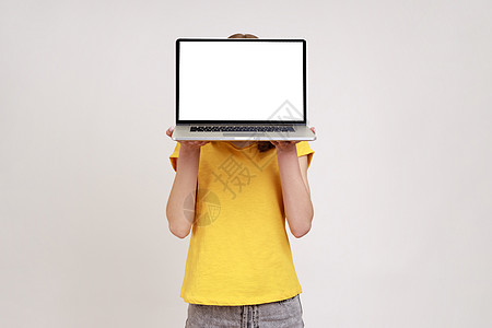 青春女性的肖像是棕色卷毛 黄色时装T恤衫隐藏在白色空屏幕笔记本电脑和广告区后面图片