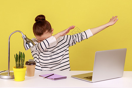 穿着笔记本电脑坐在工作场所的女办公室工作人员非常兴奋 她们表现出低调的舞蹈姿势图片