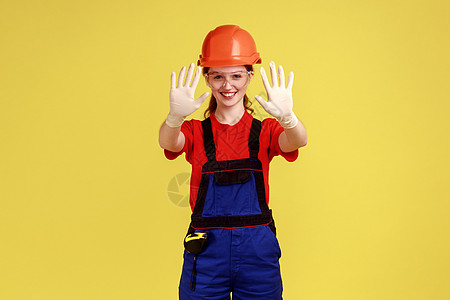 满意的建筑工妇女站在扶起的手臂上 展示她的橡皮手套 保护手图片