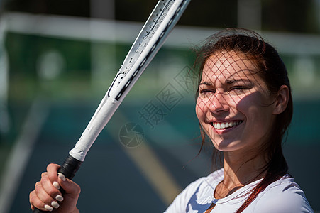 在阳光明媚的一天 美丽的微笑着美丽和笑容的女人 她脸上有网球拍打的影子运动服球拍女孩精力运动员活力闲暇训练法庭晴天图片