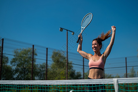 网球中微笑的女性获胜者 户外网球场的快乐女孩图片