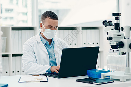 一位年轻科学家在实验室研究冠状病毒治愈方法时使用笔记本电脑 他用笔记本电脑进行治疗图片