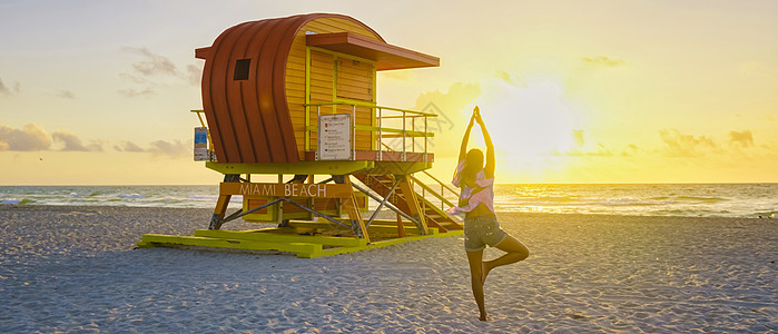 亚裔女性在日出时 在迈阿密佛罗里达南部海滩的海滩做瑜伽图片