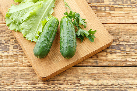 摘黄瓜摘了黄瓜和沙拉的叶子 就躺在切割板上营养食物蔬菜饮食团体绿色桌子木板收成背景
