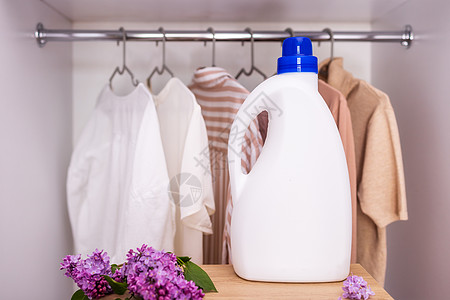 白色洗涤剂瓶装模型 放在衣橱和衣服的背景上标签女佣夹克清洁工洗涤衣架纺织品样本家庭洗澡图片