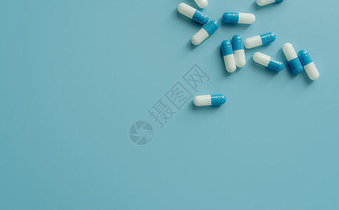 在蓝色背景上的顶视图蓝白色抗生素胶囊药丸 处方类药物 抗生素耐药性 医药行业 医药保健 药剂学概念 抗菌药物图片