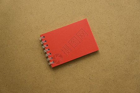 带有红色床单的笔记的红色记事本 笔记的空白空间 动作捕捉 在灰色温暖的赭石牛皮纸背景上 记事本上的假期日历注释 铭文的背景 带弹图片