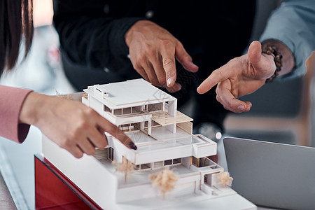 我们都在这个项目中扮演着举足轻重的角色 三位面目全非的建筑师在他们的办公室里一起制作现代住宅的比例模型图片