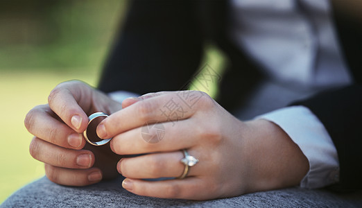 一个戒指中充满了悲伤 一位面目全非的女商务人士坐在公园里拿着结婚戒指的特写镜头图片