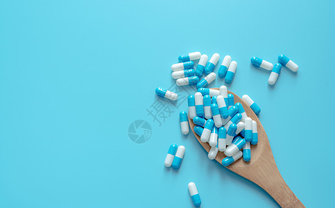 木勺上的蓝白色胶囊药丸 在蓝色背景的胶囊药片 健康话题 治疗疾病的药物 用药 医疗 医药行业 胶囊丸生产图片
