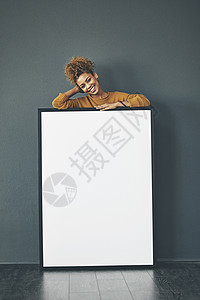 一个美丽自信的女人拿着一个空白的白板或带有复制空间的广告牌标志 微笑着站在横幅后面的快乐而迷人的女性 用海报做广告的年轻女士图片
