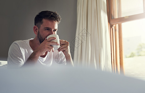 谁不喜欢一杯温暖的咖啡 一个英俊的年轻人在家里的卧室里喝咖啡图片