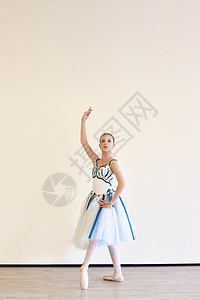 一个穿着裙子的年轻芭蕾舞女郎 在演播室练习芭蕾舞姿势图片