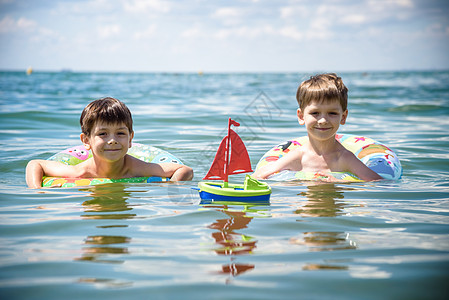游泳池里的孩子漂浮在玩具环上 孩子们游泳 为年幼的孩子们准备的七彩彩虹花车 小男孩在热带度假胜地享受家庭暑假 沙滩和水上玩具 防图片