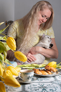 金发的中年金色抱小猫 喝茶 黄郁金香和书伴侣猫科动物拥抱朋友郁金香乐趣宠物快乐金发女郎静物图片