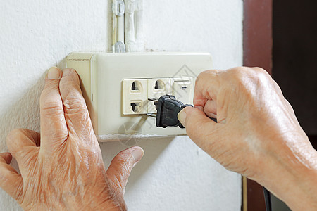 年长妇女尝试用电源插线连接电源老年病出口绳索电缆插座长者抽搐技术手指力量图片