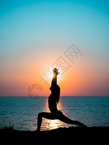 日出时分 年轻苗条的女孩在山上练习瑜伽 对抗海洋或大海 令人敬畏的日落光线中的女人剪影精神女士潮人身体生活海滩平衡海岸线太阳训练图片